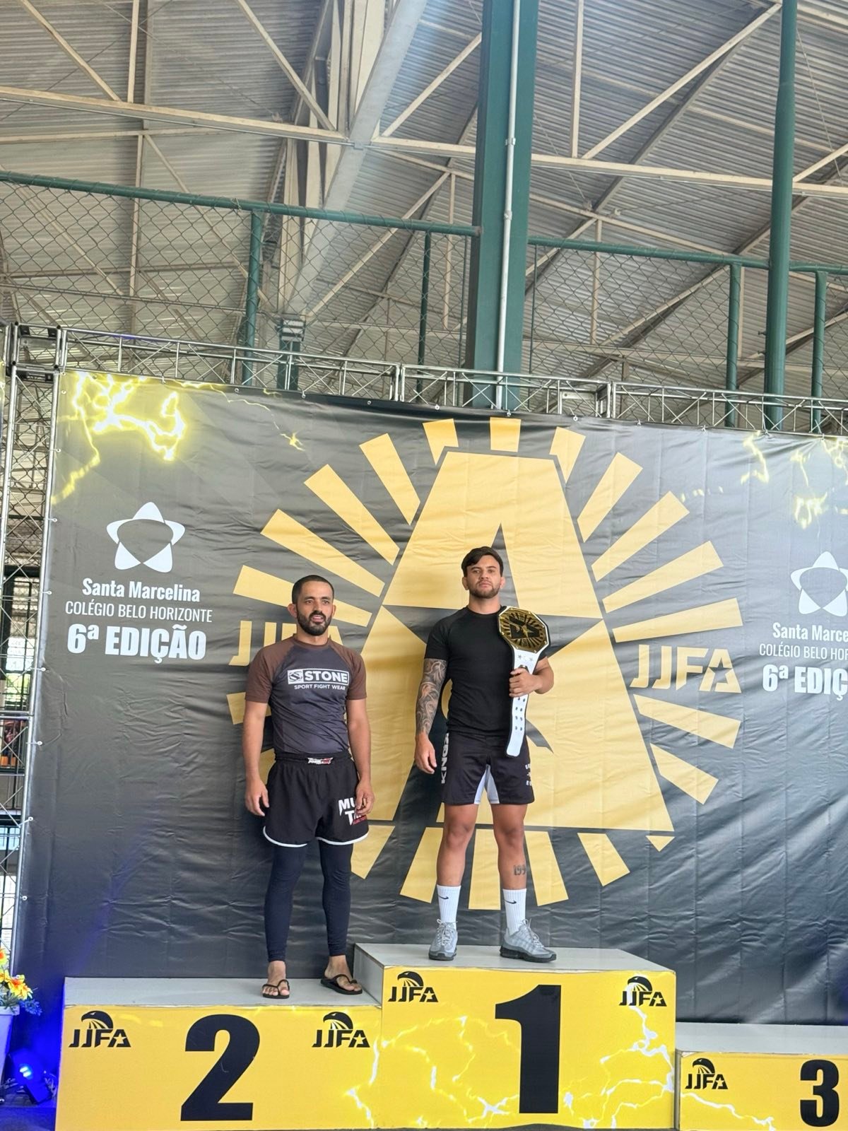 Kelinho Ávila standing on the number one podium spot with a championship belt